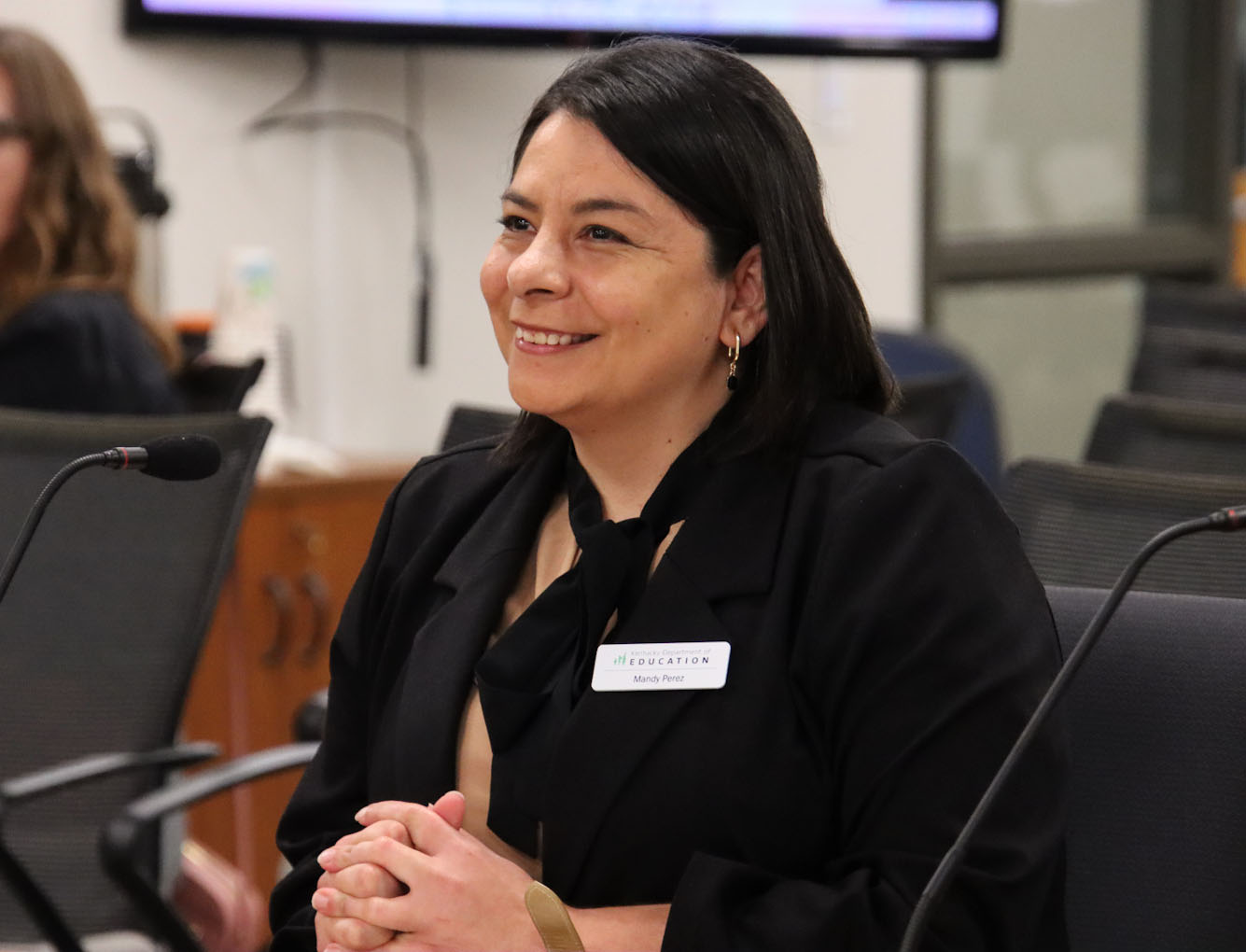 Mandy Perez smiles while sitting down in a board room chair