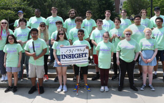 Picture of a large group of students standing on steps holding a sign reading Insight, Postsecondary Preparation Program.