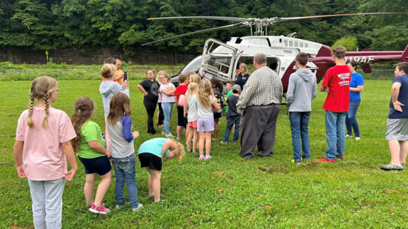 A group of kids surround a helicopter