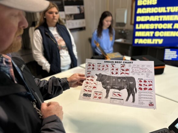 A man holds a diagram of a cow's parts