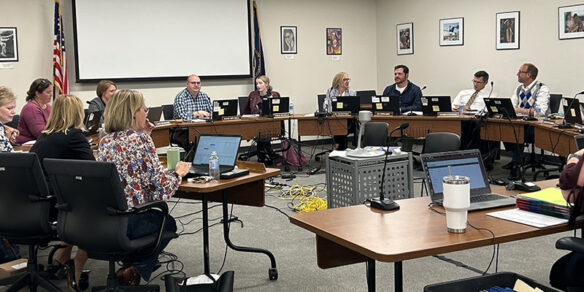 Members of the Education Professional Standards Board meeting sit around tables in a meeting room.