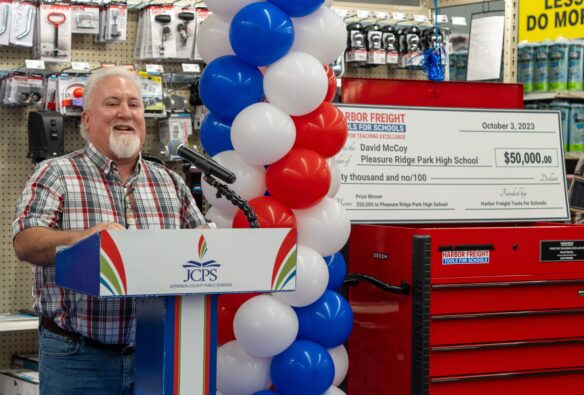 Photo of David McCoy speaking at a podium in a hardware store