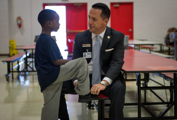 Logan County Superintendent Dan Costellow helps a student tie his shoe