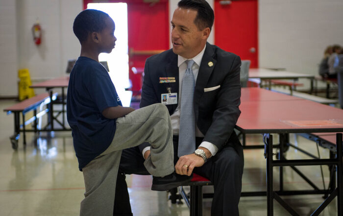 Logan County Superintendent Dan Costellow helps a student tie his shoe