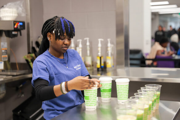 A student puts a lid on a coffee cup