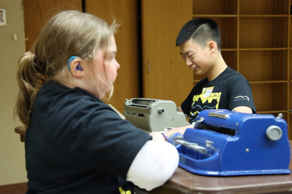 Two students work on braille machines