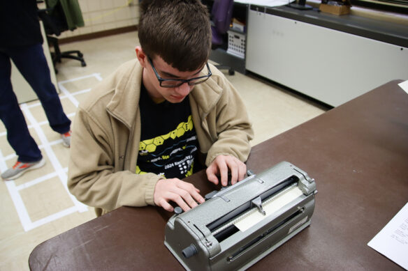 A student types on a braille machine