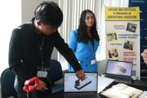 two students showing a display of their project on a computer