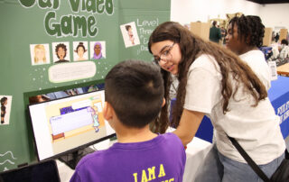 A student shows another student her project, a coding game, at the STLP State Championships