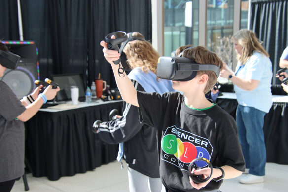 A child holds VR joysticks while wearing a VR headset
