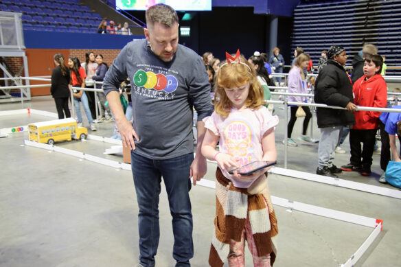 A volunteer helps a girl with a tablet