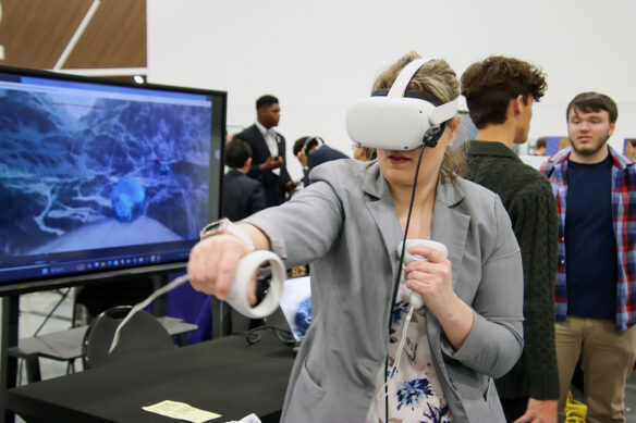 A woman extends her fist while wearing a virtual reality headset