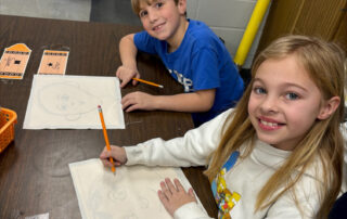 Two students draw on quilt squares