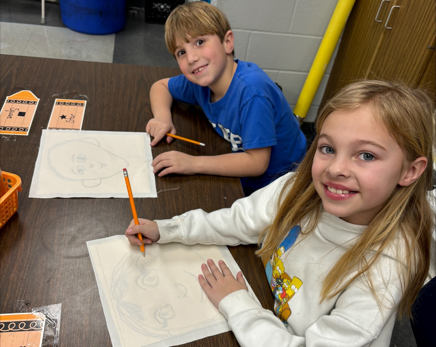 Two students draw on quilt squares