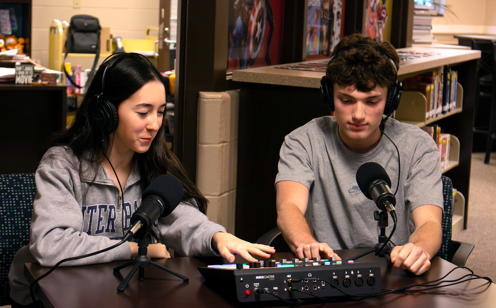 Two students work on a podcasting audio console