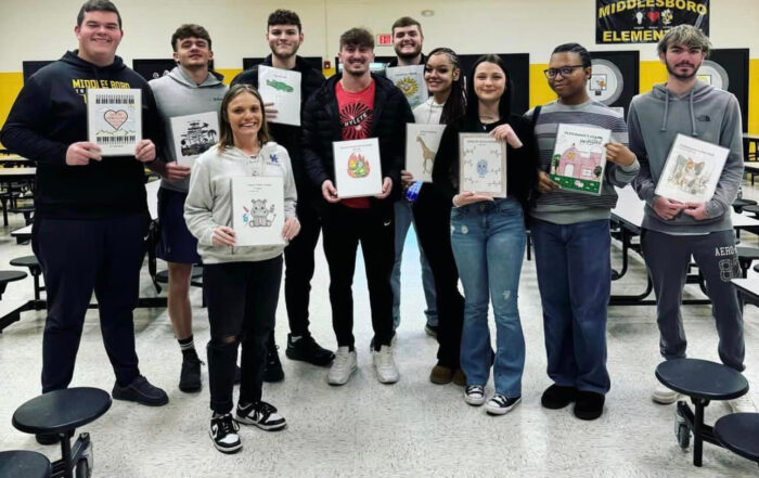 A group of students pose for a photo, holding books