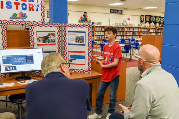 Christian Jackson makes a presentation in a library to two people who are sitting down