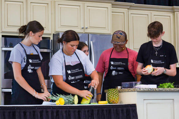 A group of students wearing black aprons perform various cooking tasks