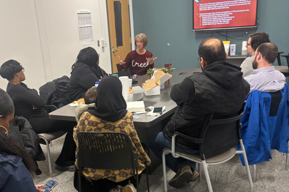 A group of people meet in a room, sitting around a table