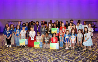 A group made up of dozens of people, some holding signs, pose for a group photo