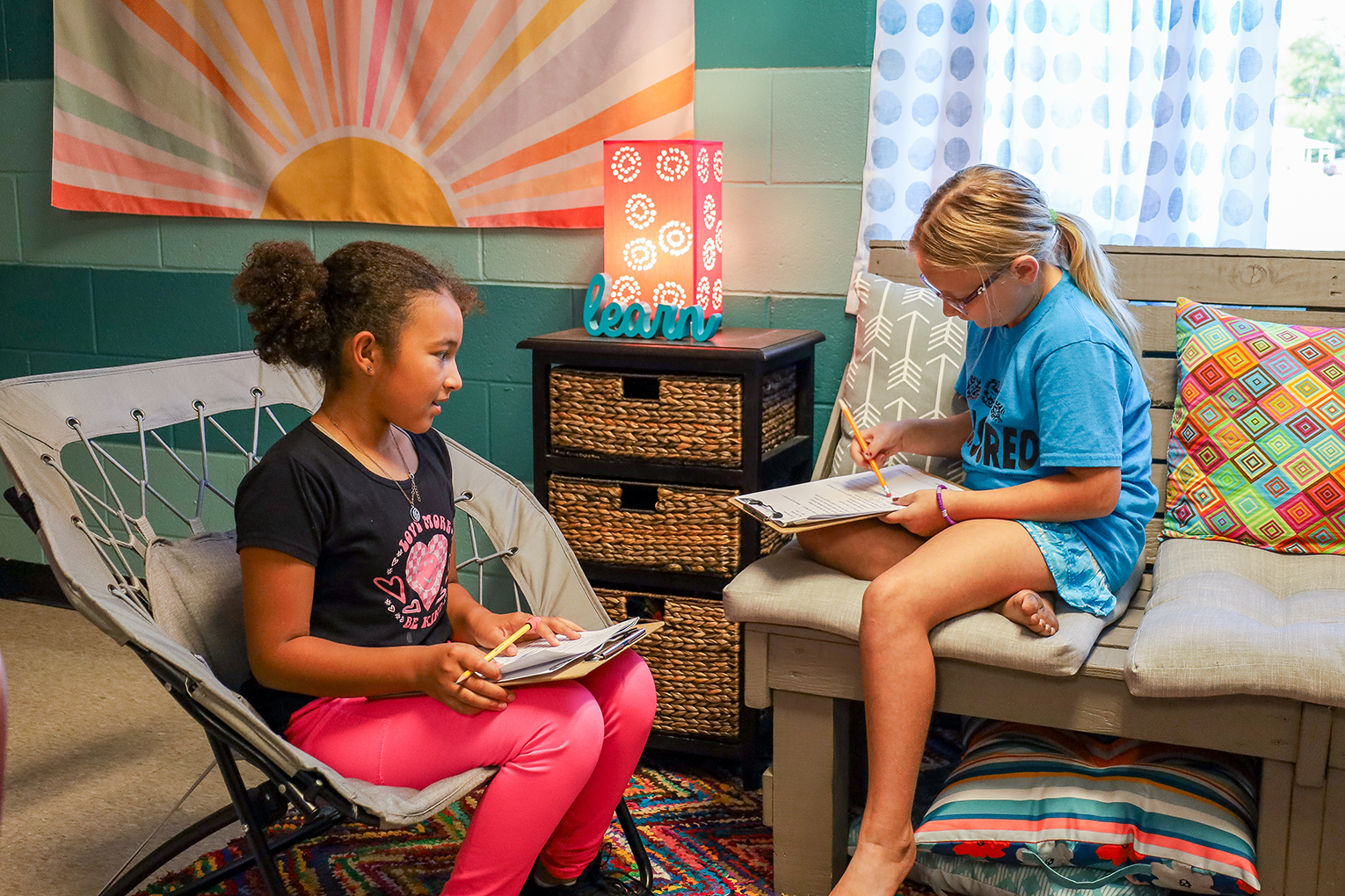 Two kids sit in a room and read books
