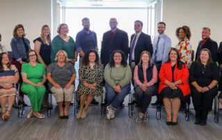 A large group of 23 men and women smile and pose for the picture.