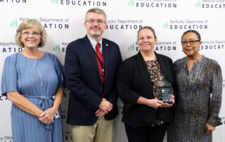 Beth Hargis, Robbie Fletcher, Hope Harp holding a glass trophy and Sharon Porter Robinson pose for a picture.