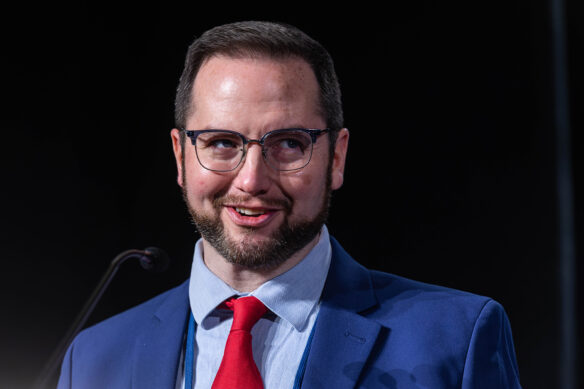 A man in a blue suit speaks into a microphone