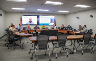 KBE members sit around the board room