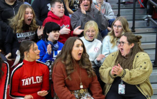 Sydney Newton opens her mouth in surprise as students sitting around her in the bleachers cheer and clap for her.