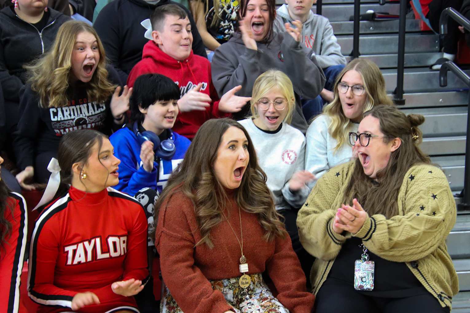 Sydney Newton opens her mouth in surprise as students sitting around her in the bleachers cheer and clap for her.