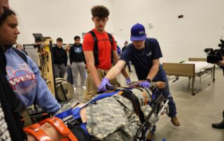 A student extends his hands out on a mannequin on a stretcher