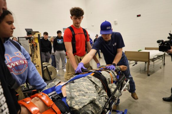 A student extends his hands out on a mannequin on a stretcher