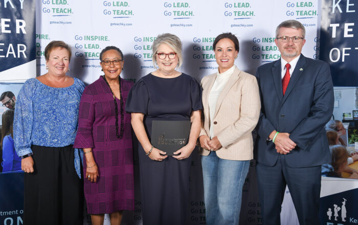 From left to right, Lu Young, Sharon Porter Robinson, Jacqueline Coleman and Robbie Fletcher pose for a photo as Coffey holds a black folder with the Kentucky Department of Education logo on it