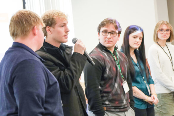 Students with a microphone talking in front of a crowd