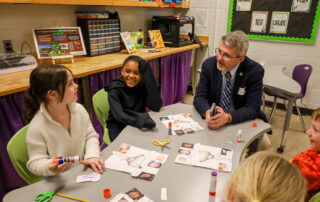 Commissioner of Education Robbie Fletcher works with Tulley Elementary 1st-graders Amelia Peoples, from left, and DJ Chackles while they learn about chicks.