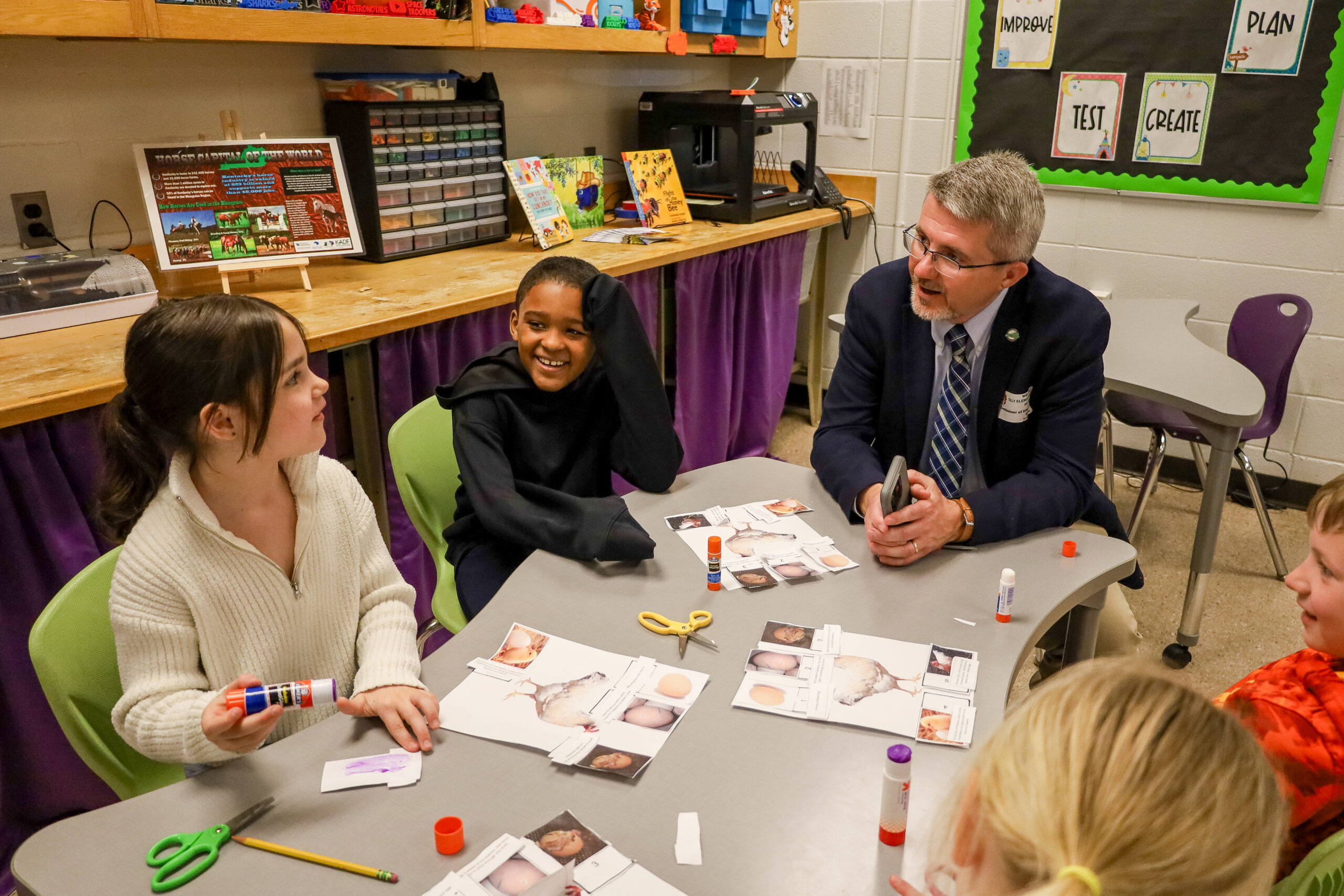 Commissioner of Education Robbie Fletcher works with Tulley Elementary 1st-graders Amelia Peoples, from left, and DJ Chackles while they learn about chicks.