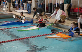 three kayaks piloted by students in a swimming pool