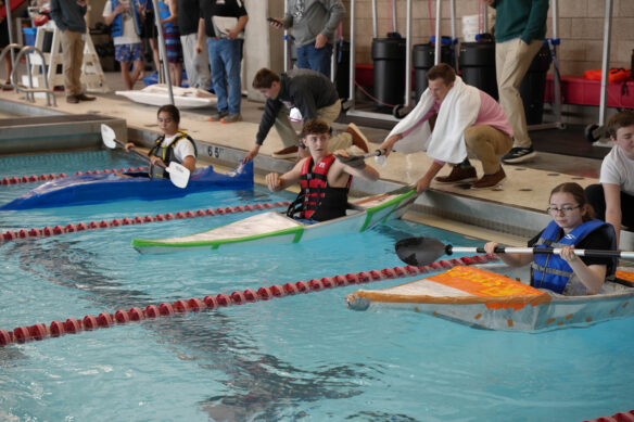 three kayaks piloted by students in a swimming pool