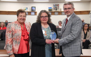 Rhonda Logsdon, holding a glass award, poses for a photo with Lu Young and Robbie Fletcher.