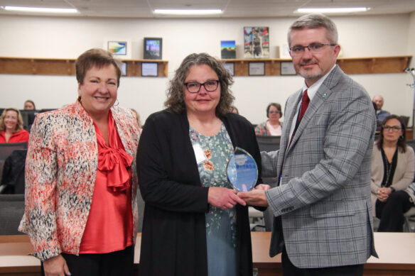 Rhonda Logsdon, holding a glass award, poses for a photo with Lu Young and Robbie Fletcher.
