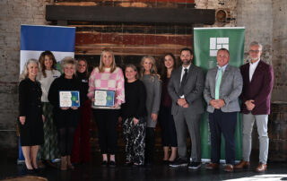 A group of people pose for a photo, and a couple people are holding certificates