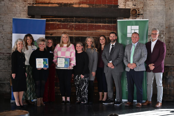 A group of people pose for a photo, and a couple people are holding certificates