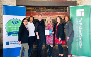 Six women pose for a group photo together while one woman in the middle holds a certificate