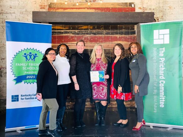 Six women pose for a group photo together while one woman in the middle holds a certificate
