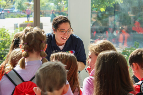 A woman smiles in front of a group of kids