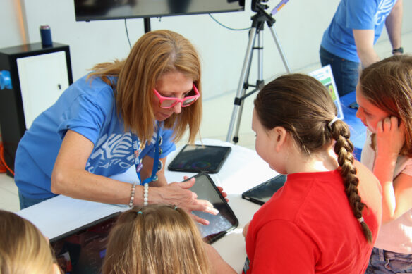 A woman points to a table in front of a group of kids