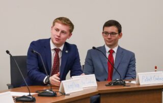 Two students sitting at a table talking into a microphone
