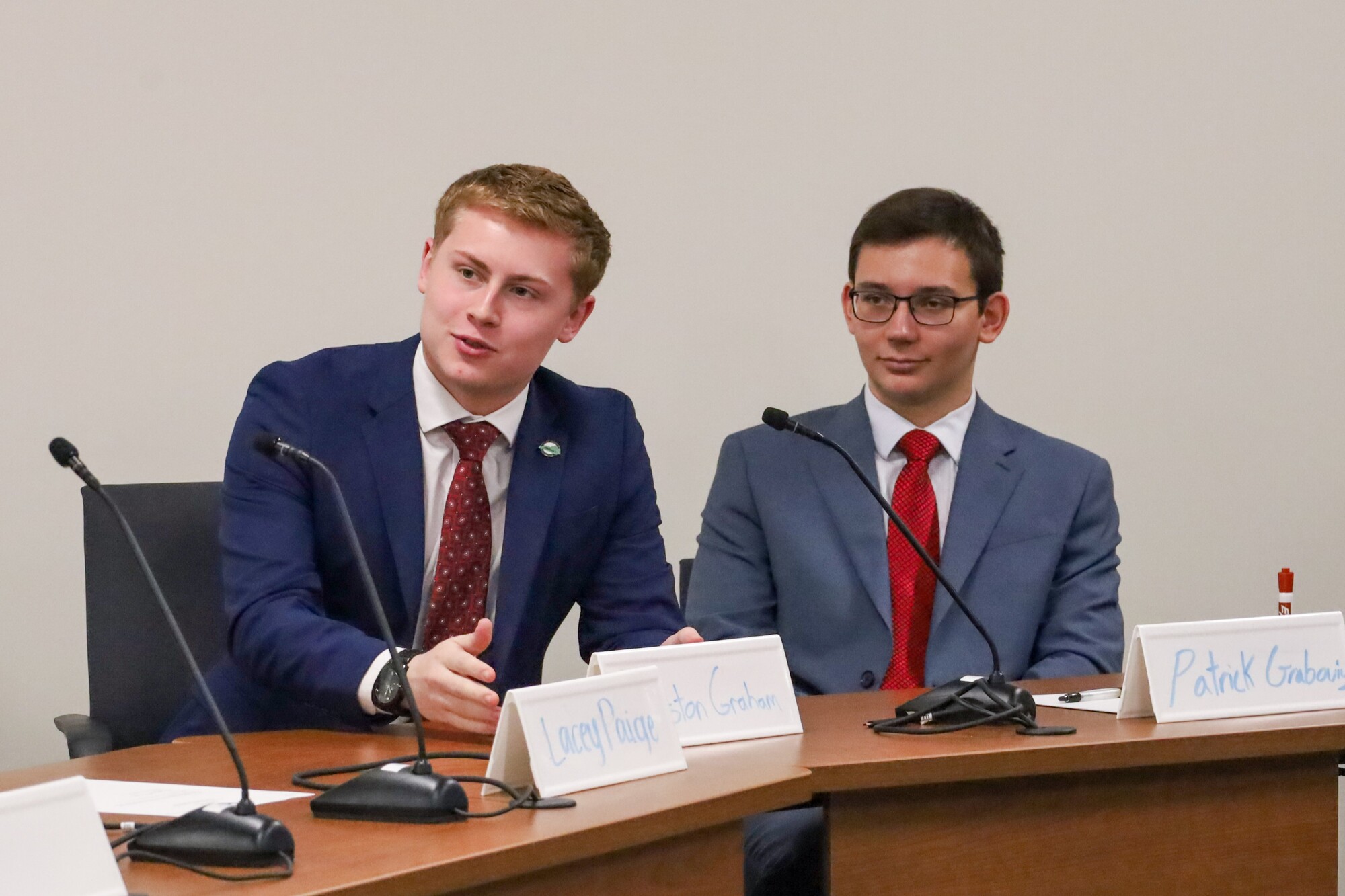 Two students sitting at a table talking into a microphone