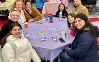 A group of people sit at a table and smile for a photo